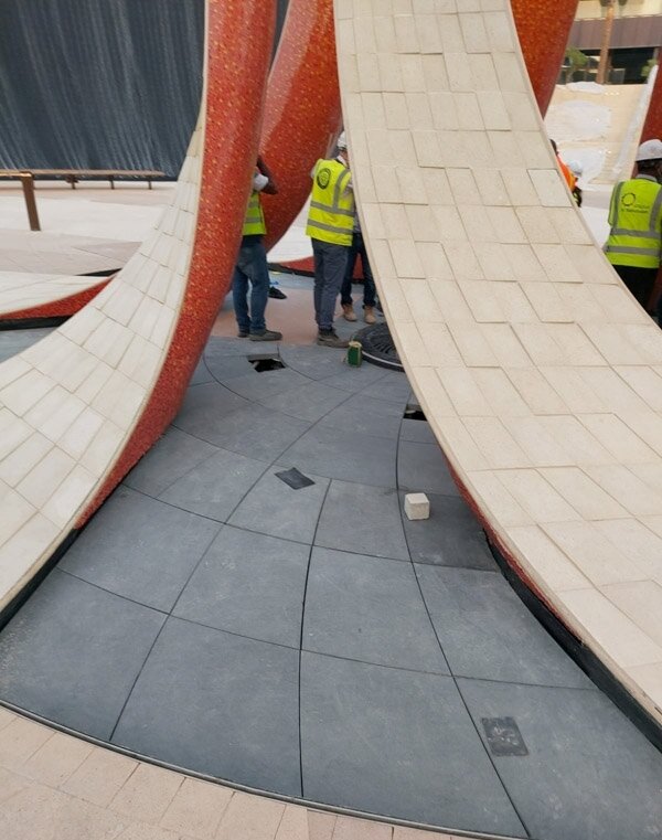 Montaje de suelo de piedra alrededor de una escultura arqueada en la Expo 2020
