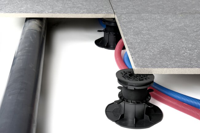 Instalación de agua y electricidad conducida bajo terraza con suelo técnico con plots soporte
