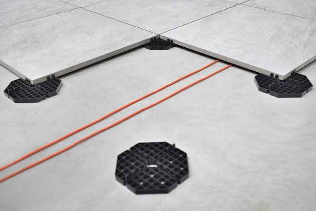 Instalación eléctrica oculta bajo terraza con suelo técnico con baldosas sobre soportes de altura fija