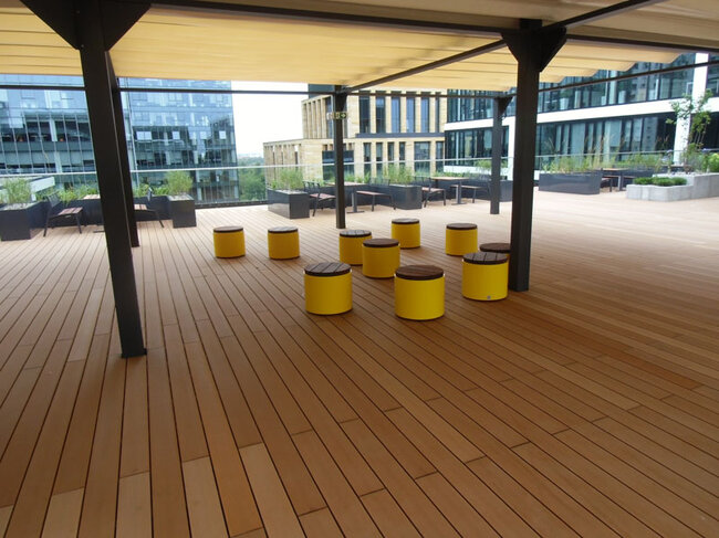Espacio común en la azotea de un edificio de oficinas realizado con tablas compuestas