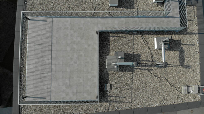 Vista de dron de una terraza en un tejado plano transitable con baldosas de gres sobre plots soporte