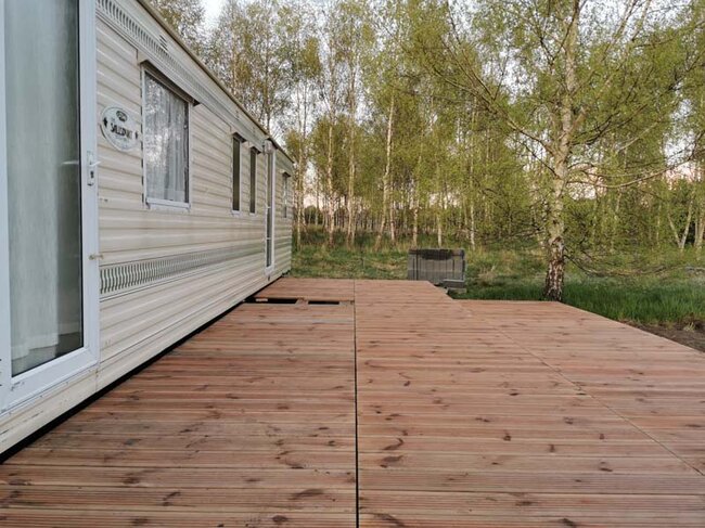 Terraza junto a la caravana de madera natural sobre plots soporte de terraza max