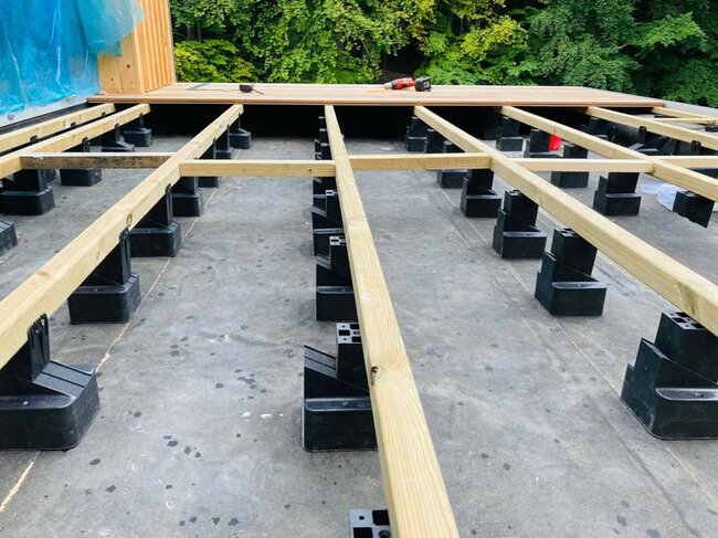 Soportes regulables sobre baldosa de terraza con vigas de terraza espaciadas uniformemente