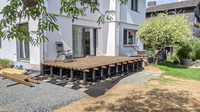 Construcción de terraza de madera sobre plots soporte regulables altos junto a la casa