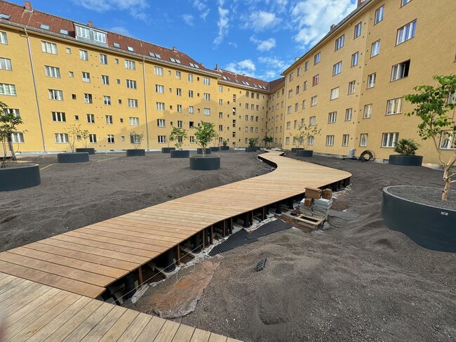 Construcción de un sendero sinuoso con tablas de madera sobre soportes regulables en el patio