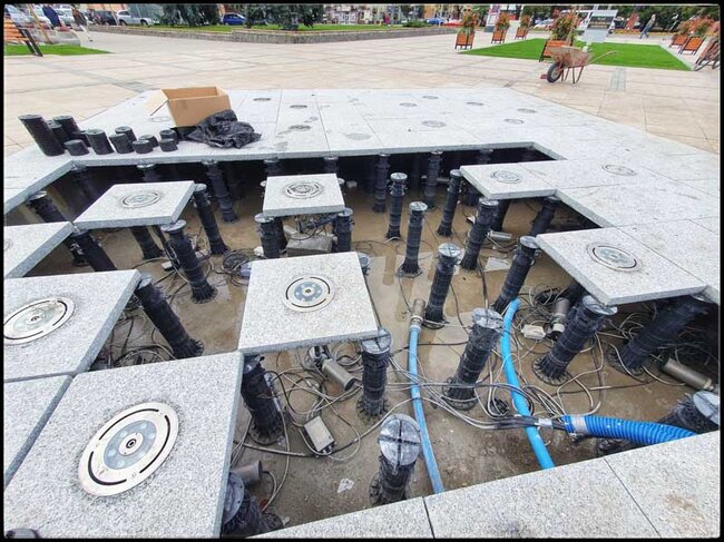 Granite slabs with nozzles laid on high adjustable pedestals of a ventilated terrace.