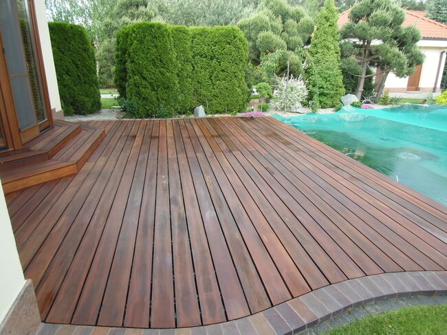 Acabado de terraza de jardín con tablas de madera y borde de adoquines.