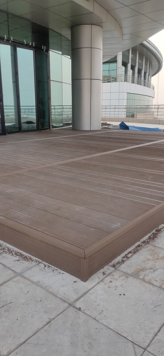 Terraza con tablas de composite sobre elevación junto a un edificio moderno