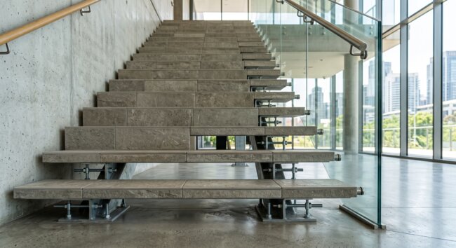 Modernas escaleras de piedra y barandilla de vidrio en un interior industrial