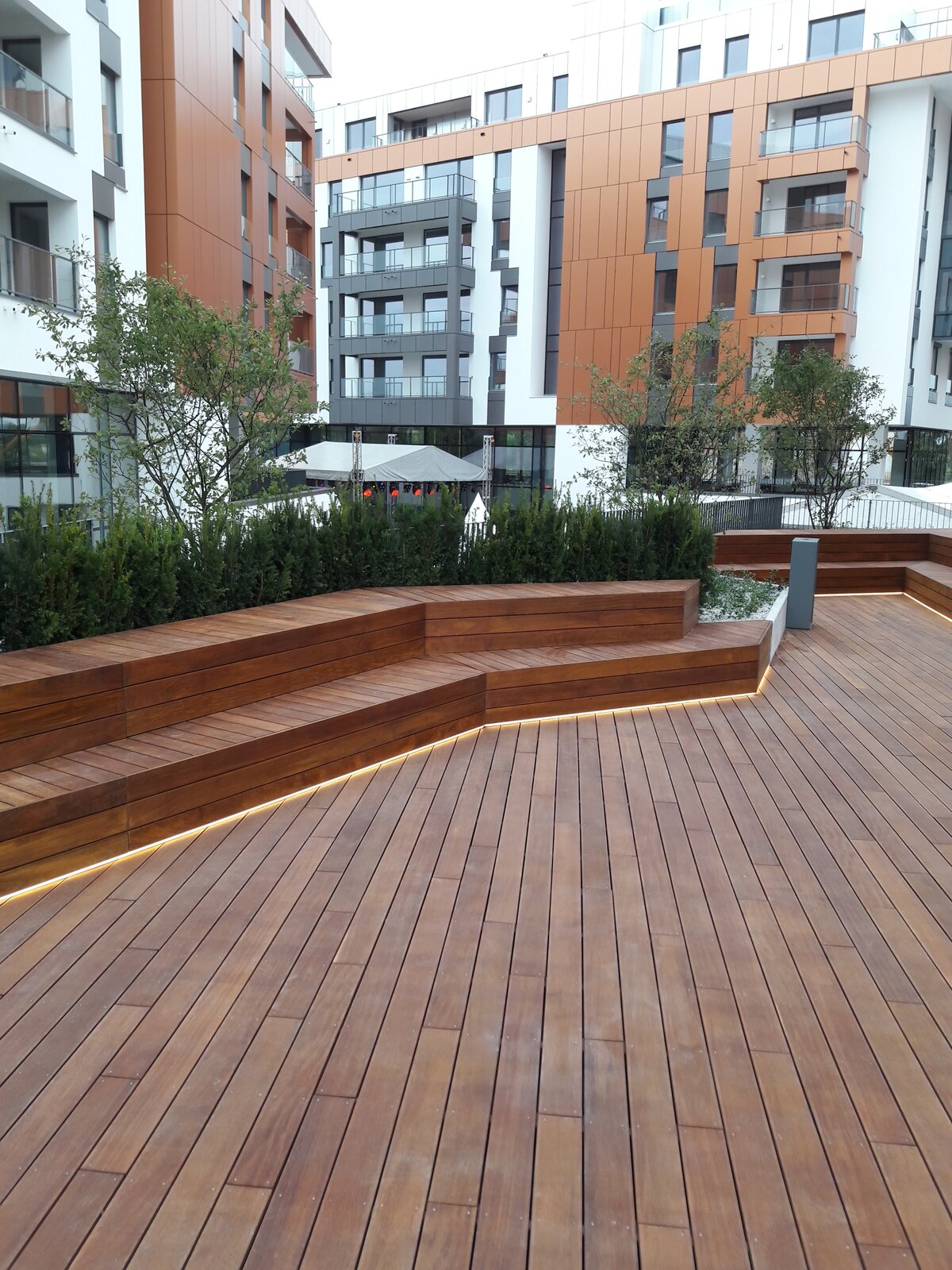 Modern terrace with wooden benches and LED lighting against a backdrop of apartment buildings