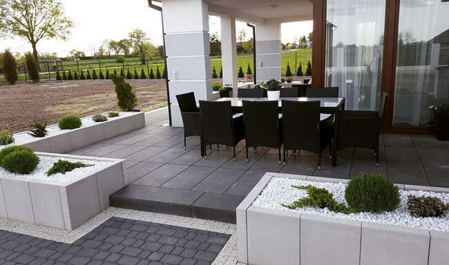 Modern terrace with dark ventilated pavers and garden furniture