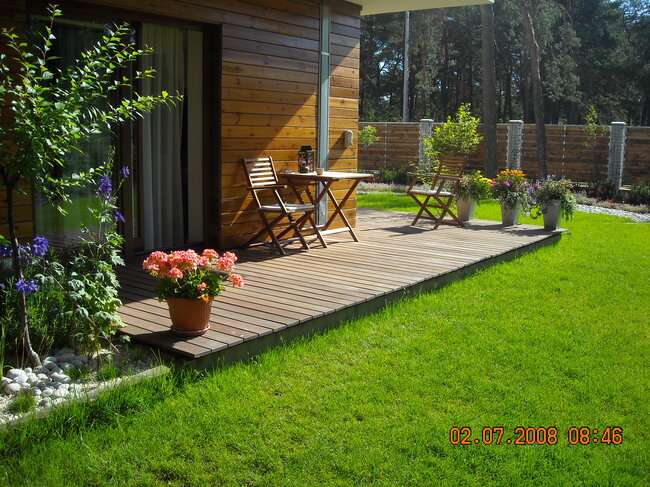Terraza de madera en el jardín con muebles de terraza y flores