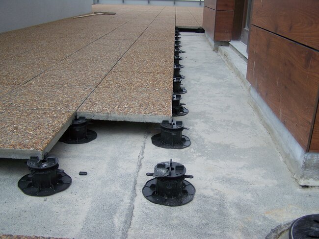 Baldosas de terraza con árido sobre soportes regulables negros