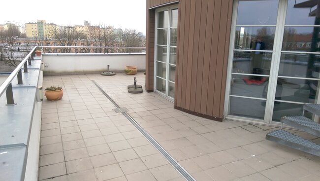 Terraza grande con baldosas y desagüe lineal en la azotea del edificio