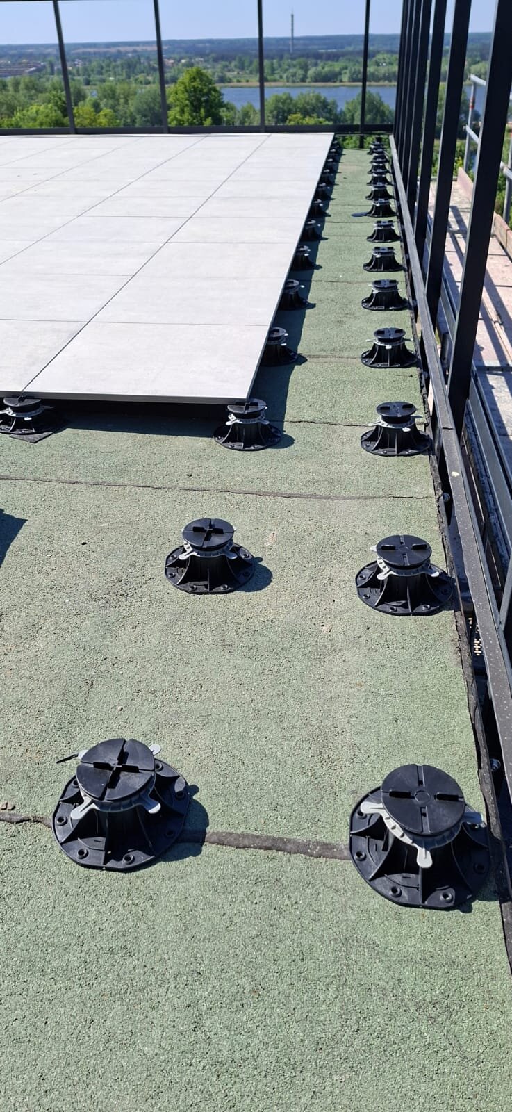 Montaje de baldosas cerámicas sobre plots soporte regulables en terraza de azotea