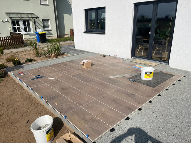 Construcción de terraza con suelo técnico con baldosas de gres imitando madera junto a la casa