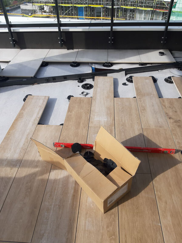 Montaje de terraza con suelo técnico con baldosas de gres imitación madera sobre plots soporte
