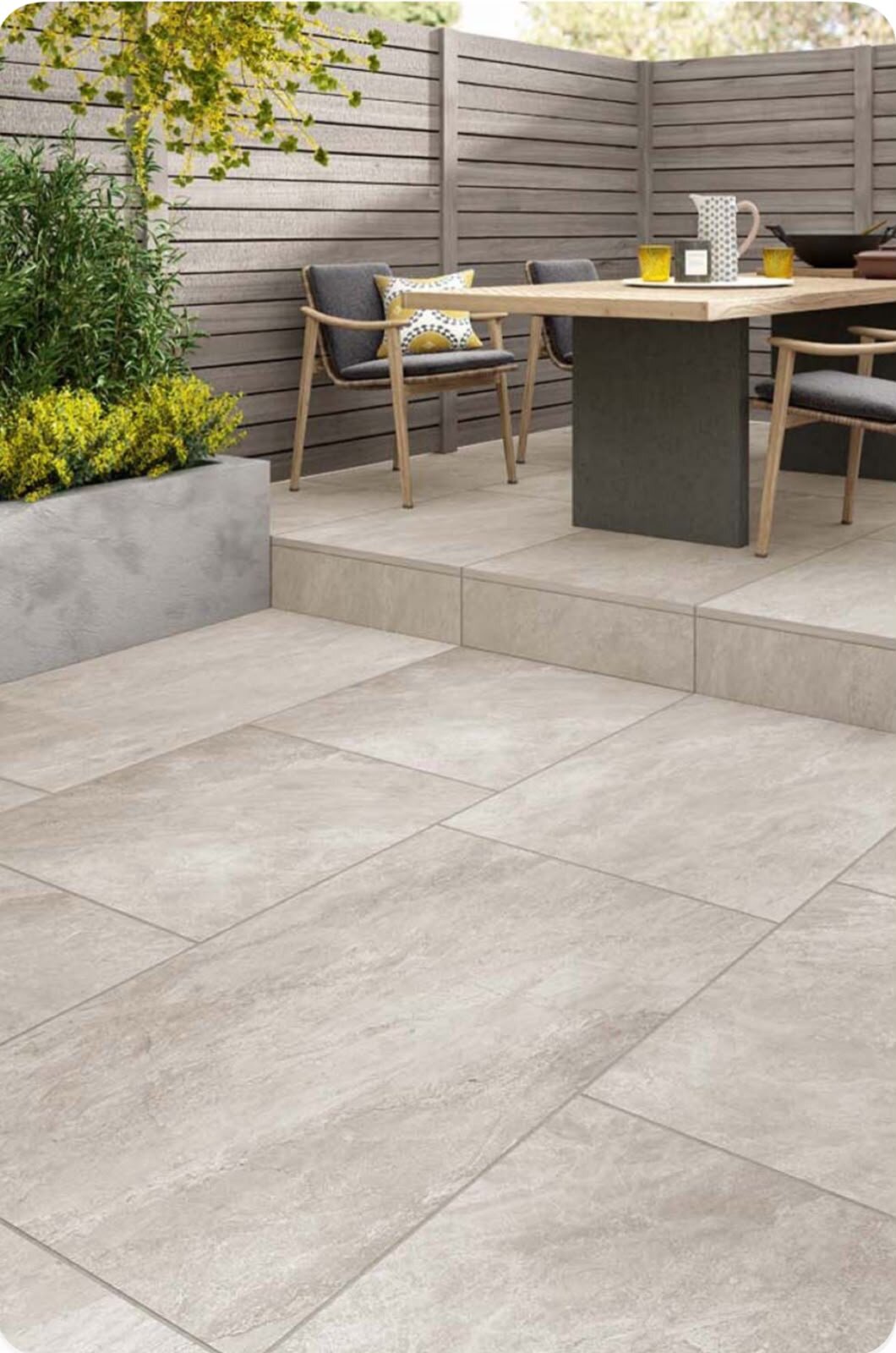 Dos niveles de terraza con baldosas de gres claras y muebles de jardín