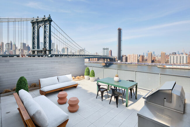 Lujosa terraza en la azotea con muebles y vista al puente de Manhattan