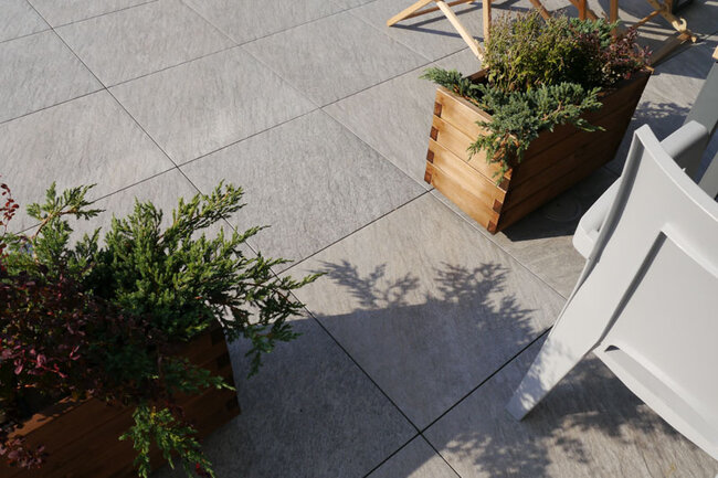 Baldosas claras de gres en terraza con suelo técnico con maceteros de plantas