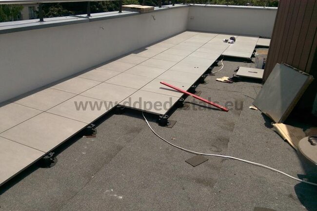 Fotografía de la instalación de una terraza con suelo técnico sobre plots soporte con el uso de baldosas.