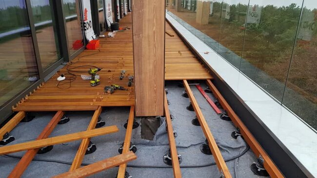 Terraza con suelo técnico de tablas exóticas sobre vigas en proceso de montaje.