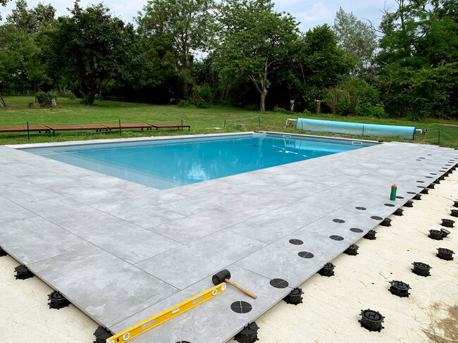 Terraza con baldosas y piscina colocada sobre el suelo sobre solera de hormigón sobre plots soporte spiral solver
