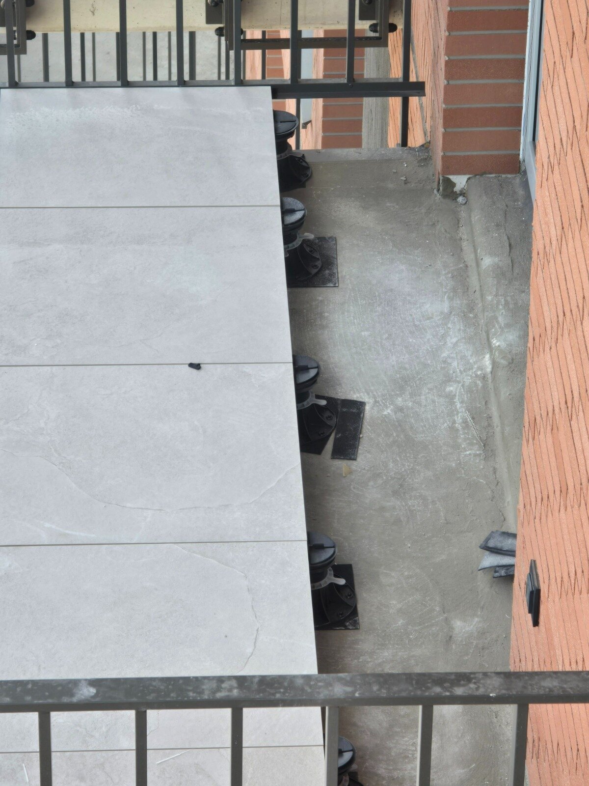 Baldosas colocadas sobre plots soporte regulables en un balcón de un edificio de viviendas.