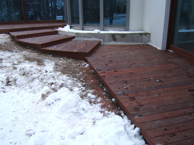 Escaleras de madera y terraza exótica en invierno cubiertas de nieve.