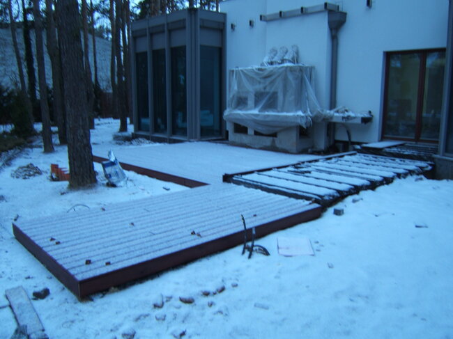 Construcción de una terraza de madera junto a una casa moderna en invierno.