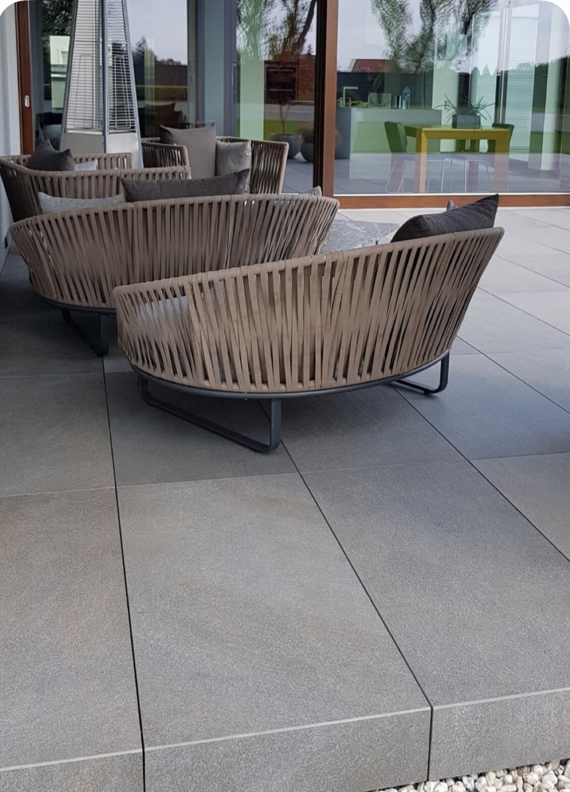 Terraza modernista con baldosas de gres equipada con muebles de jardín de mimbre