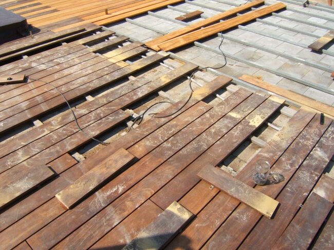 Montaje y colocación de tablas de madera para terraza sobre vigas.
