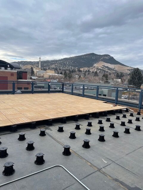 Wooden terrace panels laid on pedestals on the building's roof.