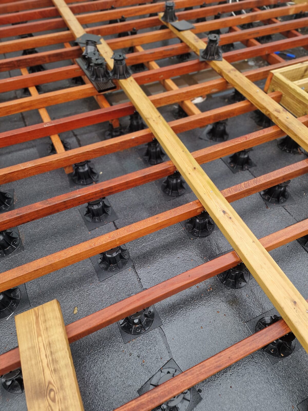 Montaje de la subestructura de una terraza de madera sobre plots soporte regulables.
