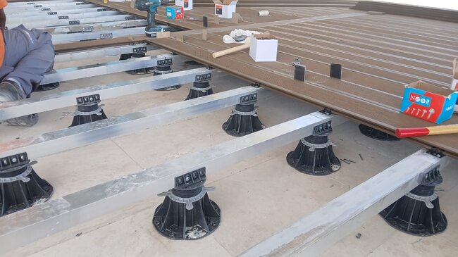 Construcción de terraza con tablas de composite sobre soportes regulables.