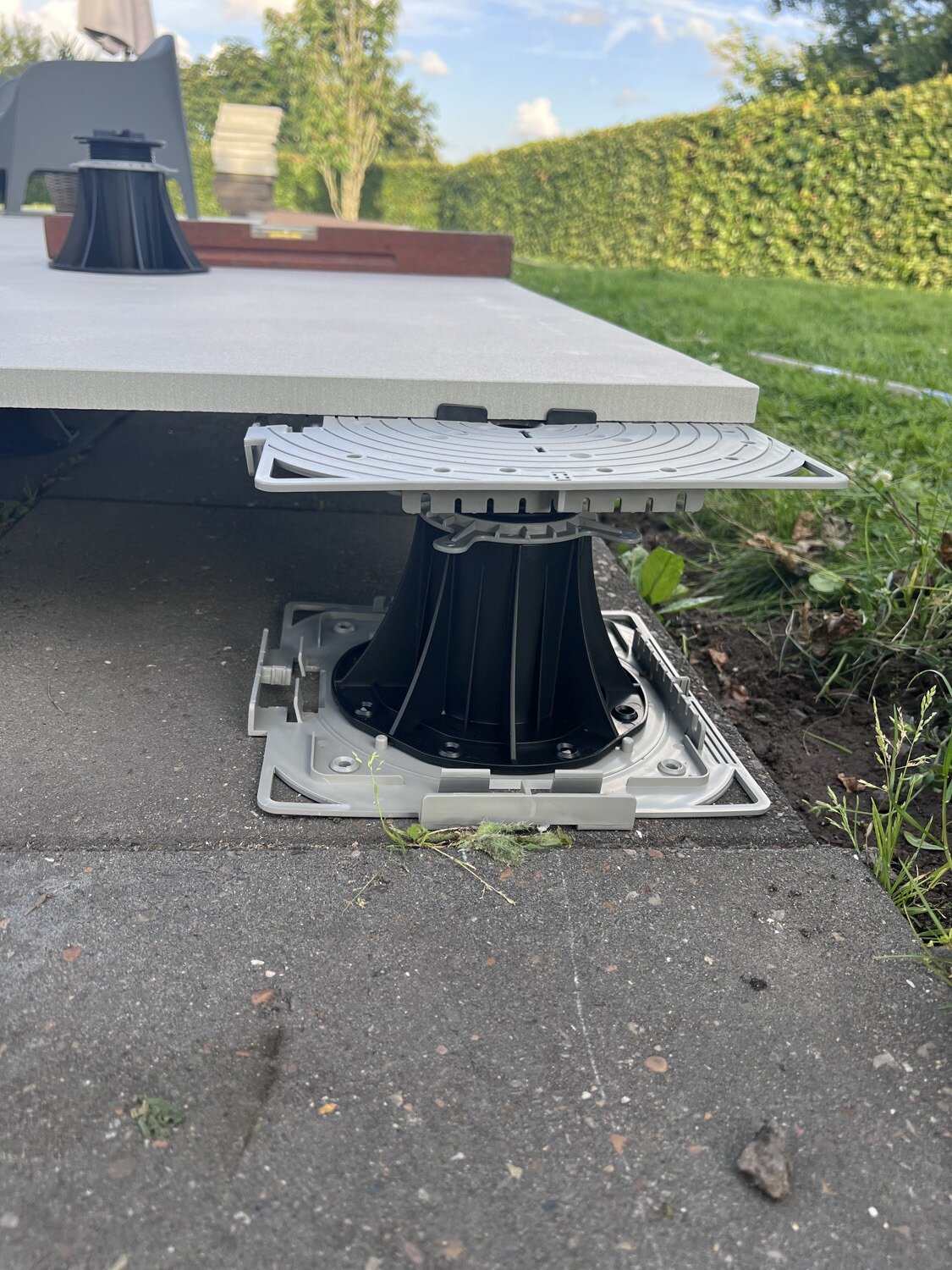 Soporte regulable para baldosa de terraza sobre base de hormigón.