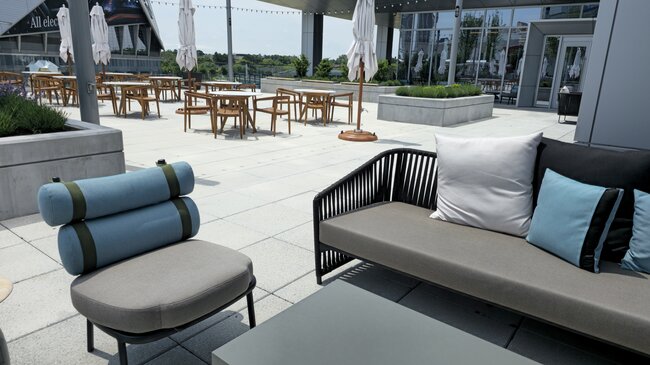Zona de descanso con muebles de jardín en una gran terraza con suelo técnico de baldosas
