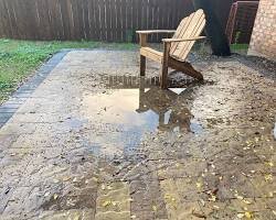 Gran charco en la terraza de adoquines debido al mal drenaje del agua.