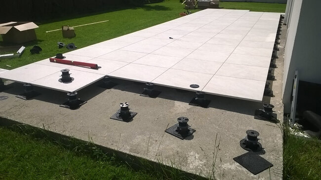 Terraza sobre el terreno sobre placa de hormigón colocada sobre plots soporte regulables