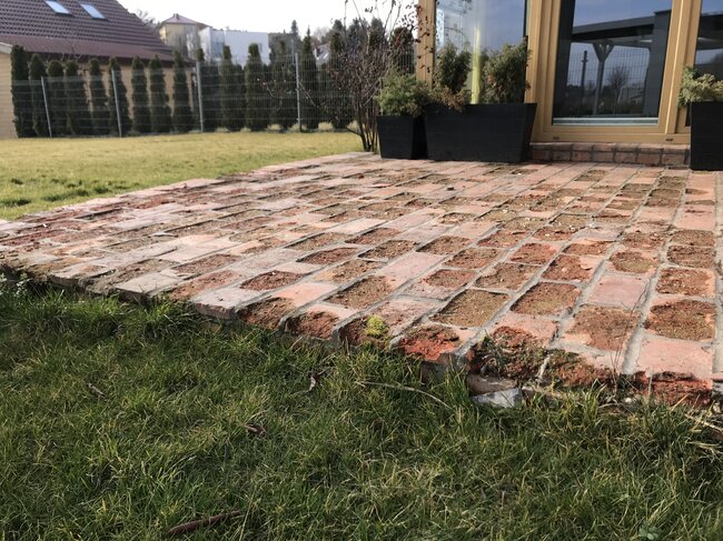 Terraza dañada con baldosas adheridas hecha de ladrillos sobre el suelo