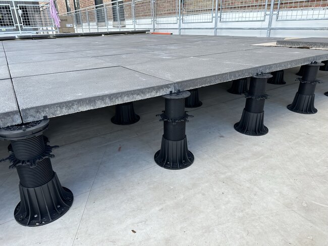 Montaje de baldosas de hormigón sobre plots soporte regulables de terraza de alta altura