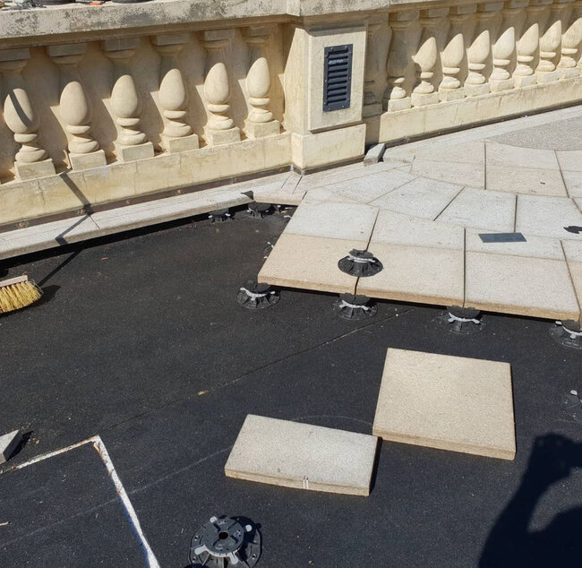 Montaje de baldosas de piedra exteriores sobre Plots Soporte de plástico regulables sobre una membrana impermeabilizante negra para tejados.