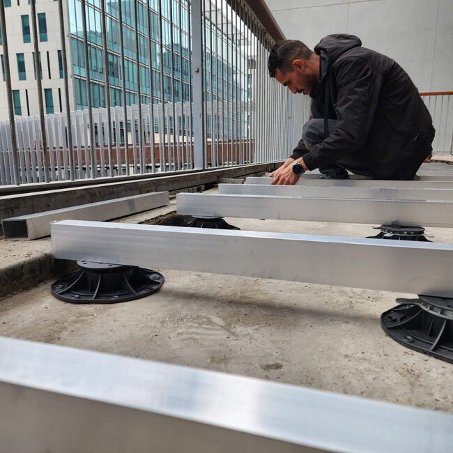 Instalación de vigas de aluminio apoyadas sobre plots soporte de terraza regulables de plástico