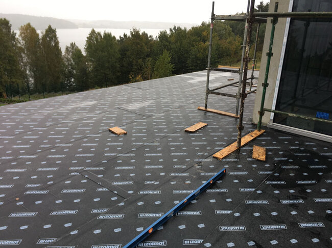 Cubierta plana en construcción con instalación de membrana impermeabilizante bituminosa.