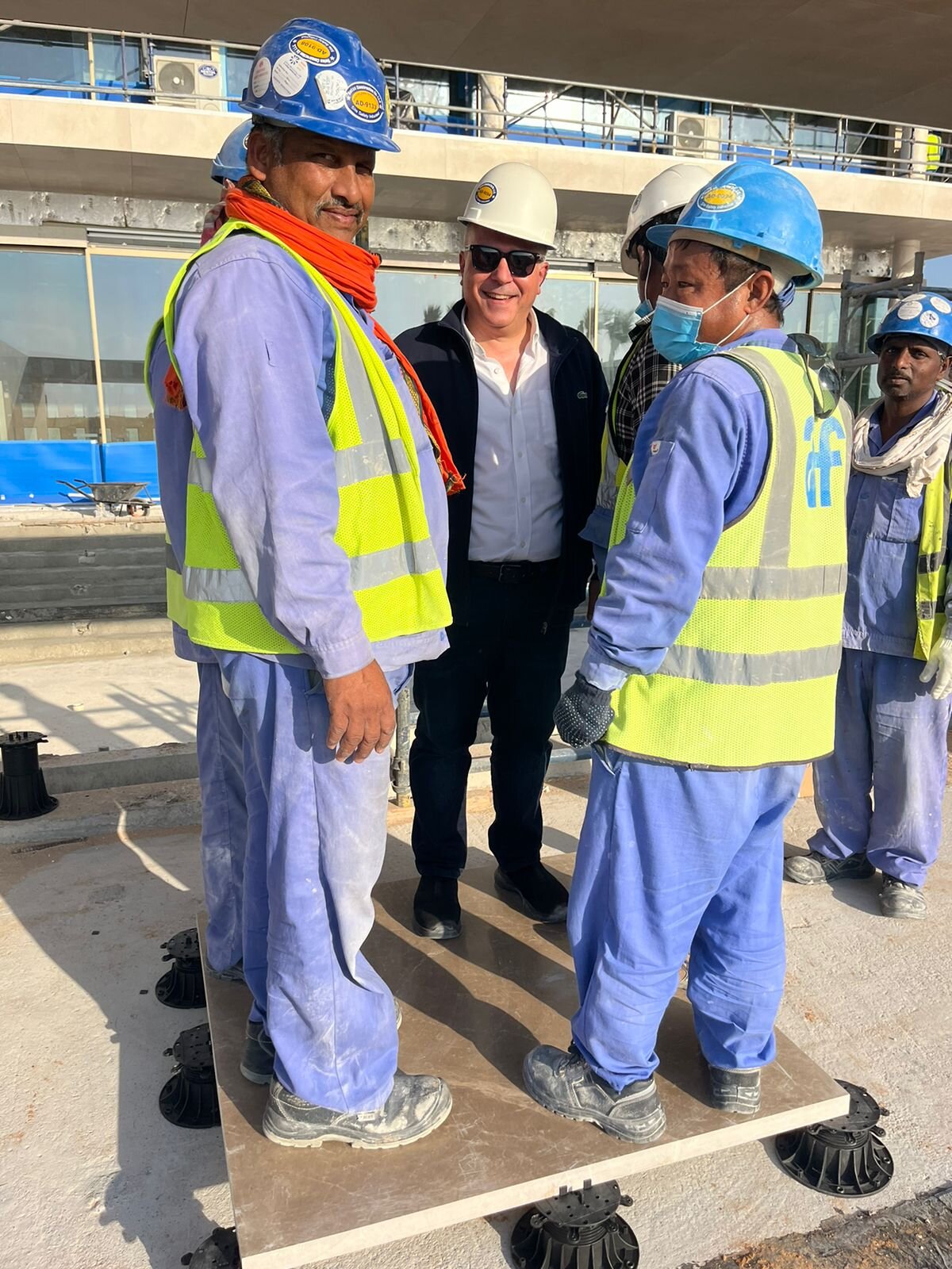 Trabajadores de la construcción realizando una prueba de carga sobre una losa de hormigón pesada colocada sobre plots soporte de terraza de plástico.