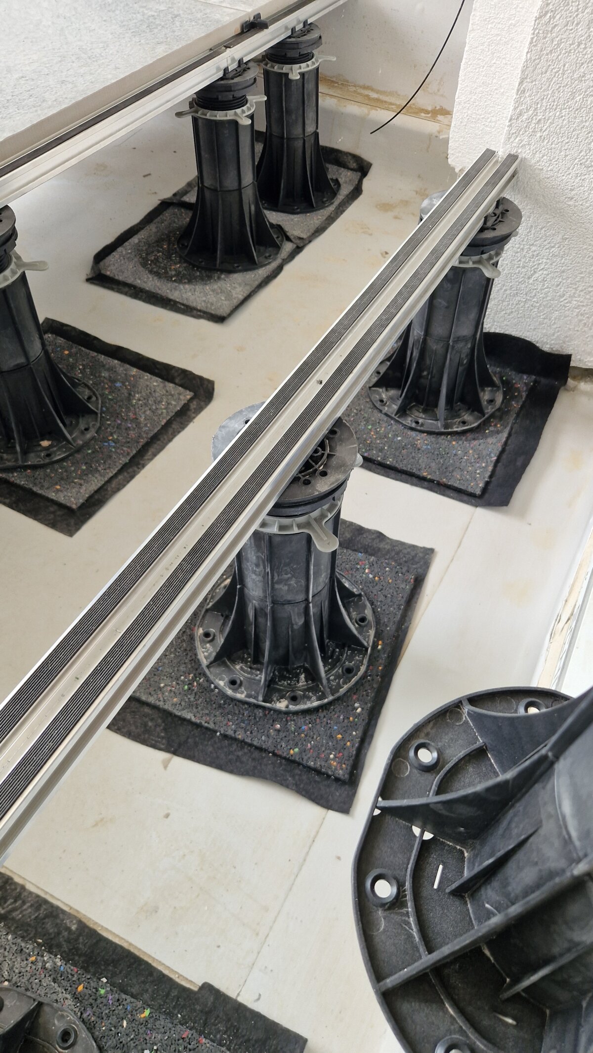 Sistema de plots soporte regulables con vigas de aluminio para el montaje de una terraza exterior elevada.