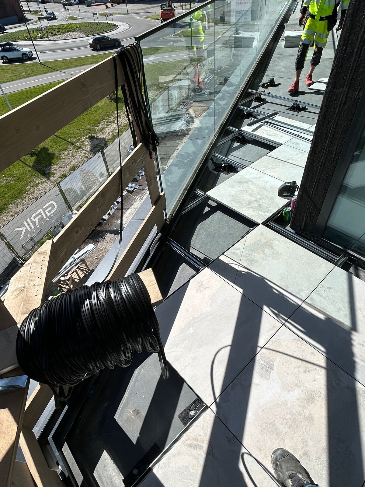 Sistema de suelo elevado de balcón en construcción con baldosas de porcelana para exteriores y plots soporte regulables.