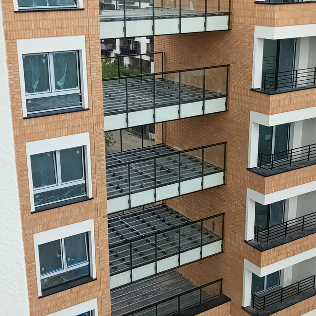 Subestructuras de balcón de varias plantas con vigas de aluminio apoyadas sobre plots soporte de terraza regulables de plástico.