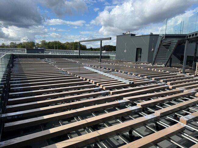 Subestructura de vigas de aluminio sobre soportes montada bajo una moderna terraza en azotea.