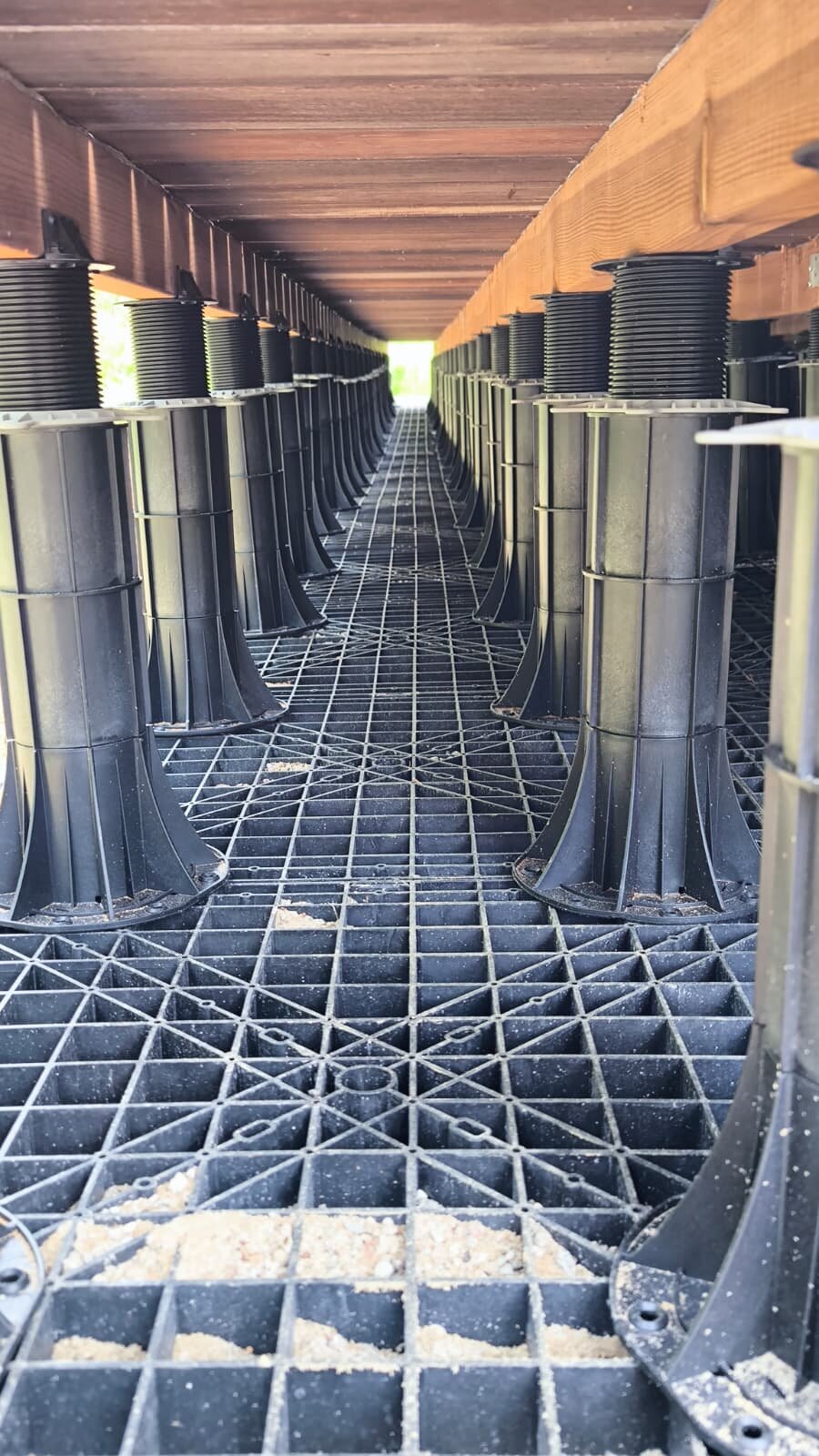 Sistema regulable de soportes de plástico instalado bajo la estructura de una terraza en azotea.